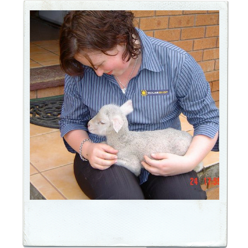 Anastasia Geneave in a Solar Shop Australia shirt with a baby lamb on her lap.